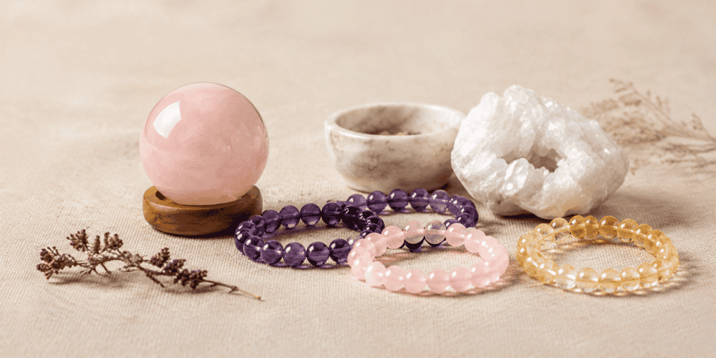 Rose quartz and assorted crystal beaded bracelets displayed with natural healing stones on soft beige background